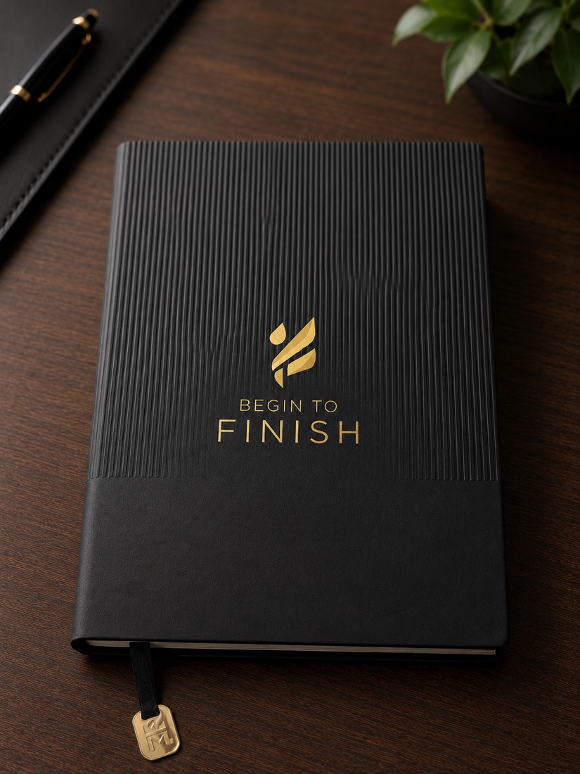 The Begin to FINISH journal — black linen cover with the gold-embossed Begin to FINISH mark and a gold ribbon marker