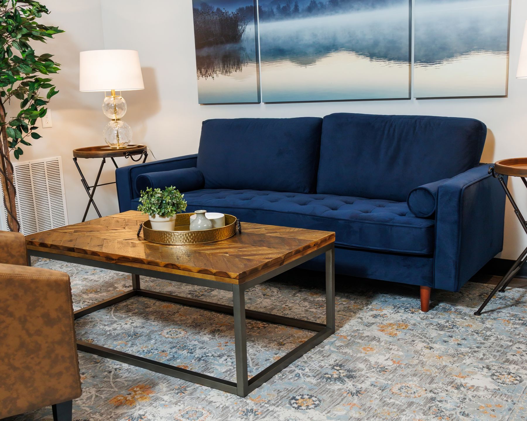 The FINISH lounge in Athens — a navy sofa beneath a misty mountain triptych; warm wood and calm, not a waiting room