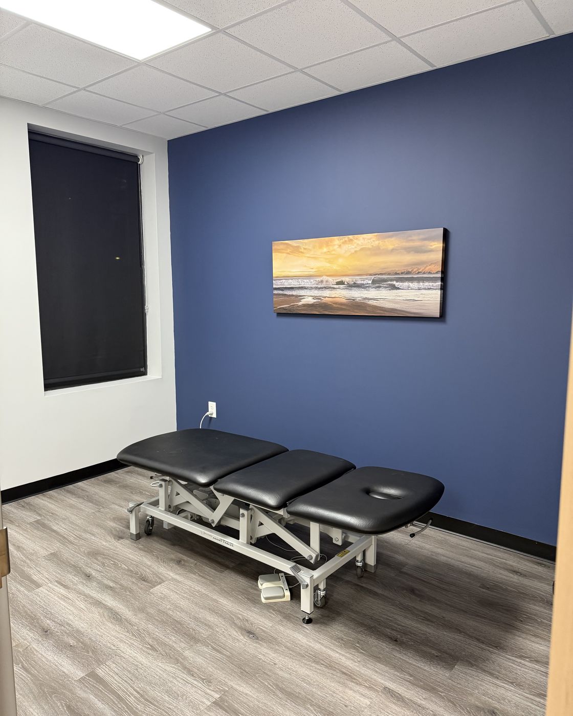A FINISH treatment room with a therapy table beneath a sunrise canvas